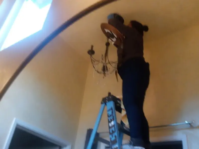 Electrician installing a chandelier in a East Franklin residence